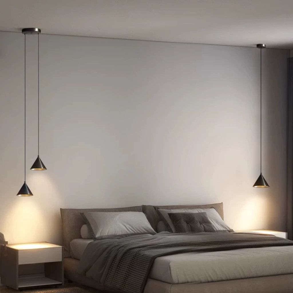 Modern bedroom scene with two black cone-shaped pendant lights hanging above a bed with neutral bedding and bedside tables.